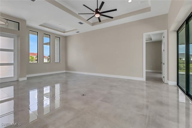 empty room featuring ceiling fan and a raised ceiling