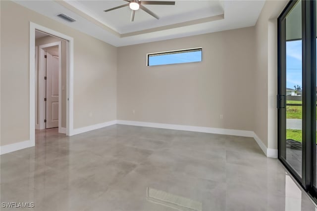 empty room featuring ceiling fan and a raised ceiling