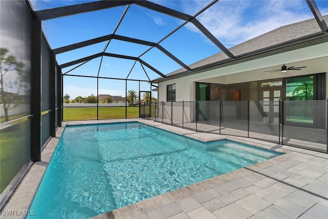 view of swimming pool with a patio area, glass enclosure, and ceiling fan