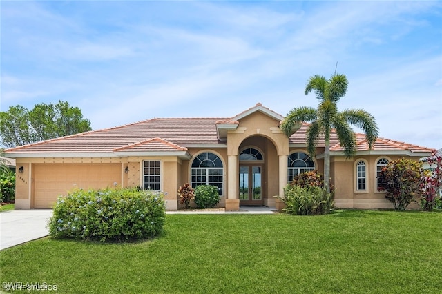 mediterranean / spanish home with a front lawn, a garage, and french doors