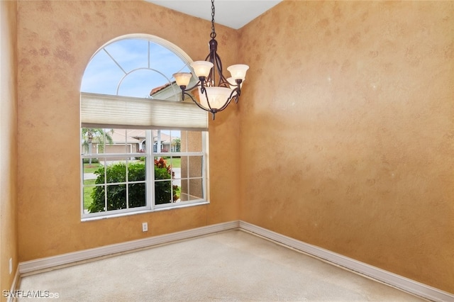 carpeted empty room featuring a notable chandelier