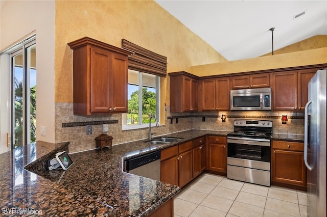 kitchen featuring high vaulted ceiling, dark stone countertops, sink, and appliances with stainless steel finishes