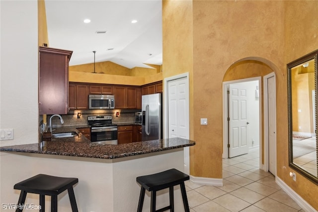 kitchen with dark stone countertops, light tile patterned flooring, stainless steel appliances, and sink