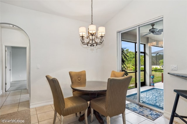 dining area with ceiling fan with notable chandelier, light tile patterned floors, and vaulted ceiling