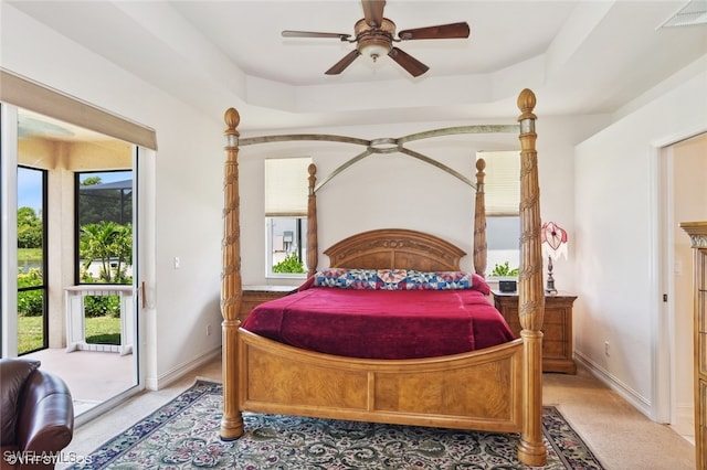 carpeted bedroom featuring a tray ceiling, ceiling fan, and access to outside