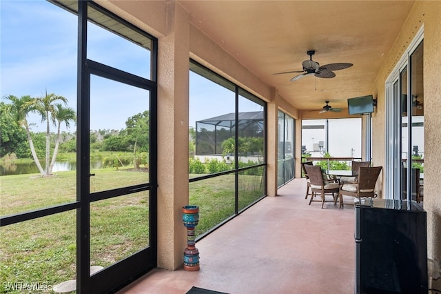 sunroom / solarium with a water view and ceiling fan