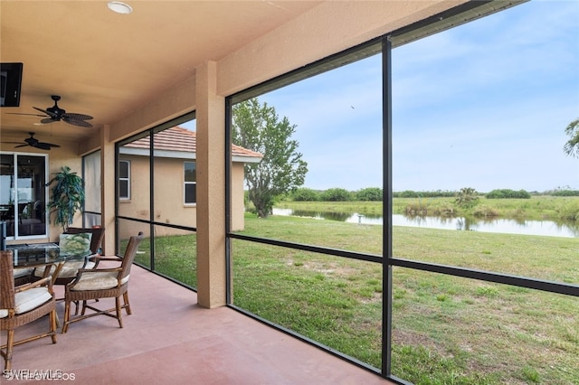 sunroom with a water view and ceiling fan