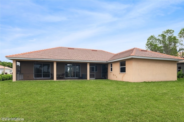 back of property with a lawn and a sunroom