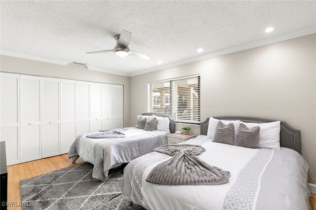 bedroom featuring ceiling fan, ornamental molding, a textured ceiling, wood-type flooring, and a closet