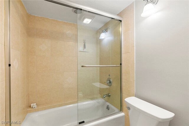 bathroom with combined bath / shower with glass door and toilet