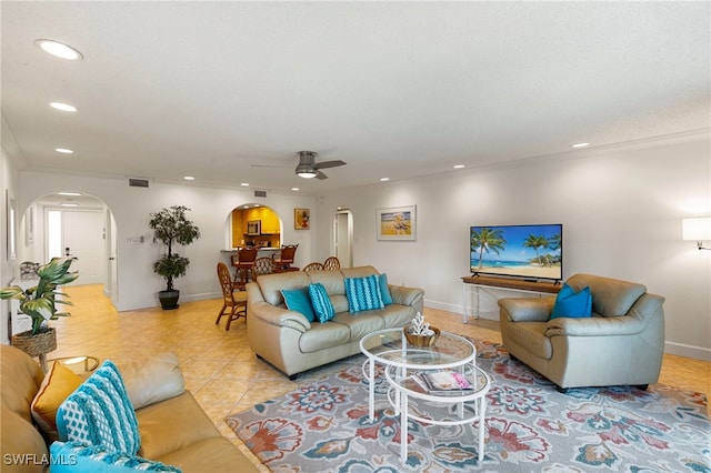 tiled living room with ceiling fan and crown molding