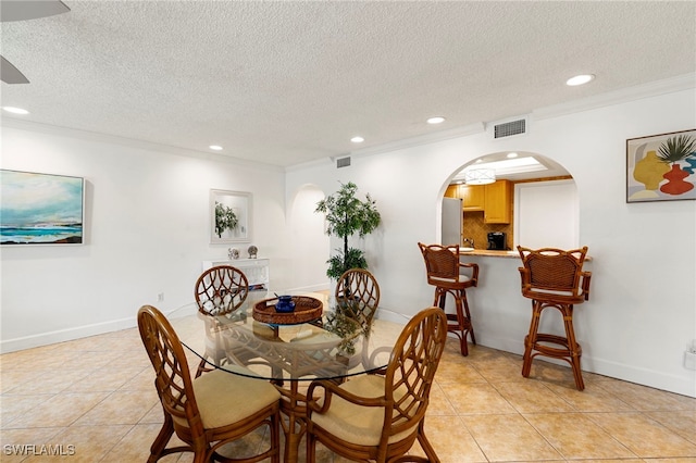 tiled dining area featuring crown molding and a textured ceiling