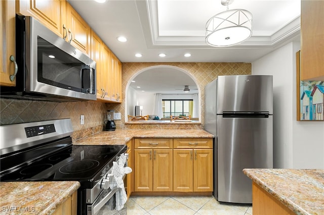 kitchen with backsplash, light stone counters, stainless steel appliances, ceiling fan, and light tile patterned flooring