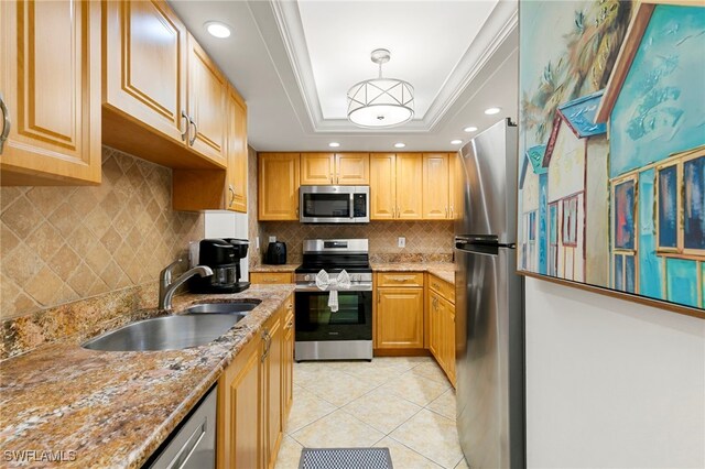 kitchen featuring ornamental molding, stainless steel appliances, a raised ceiling, sink, and pendant lighting