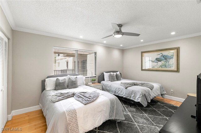 bedroom with hardwood / wood-style floors, a textured ceiling, ceiling fan, and crown molding