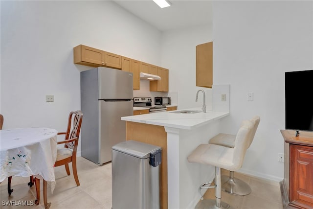 kitchen featuring a breakfast bar area, light tile patterned floors, stainless steel appliances, sink, and kitchen peninsula