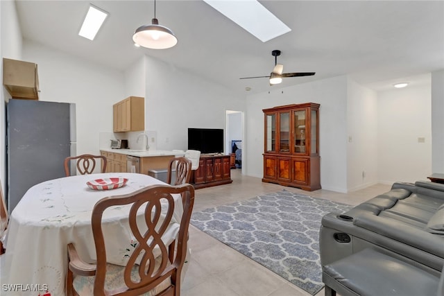 living room featuring ceiling fan, vaulted ceiling with skylight, sink, and light tile patterned flooring