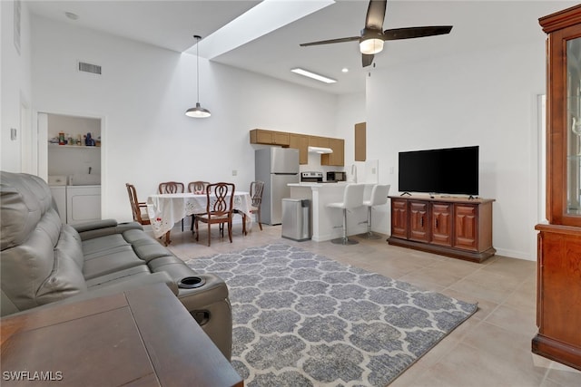 tiled living room featuring ceiling fan and a towering ceiling