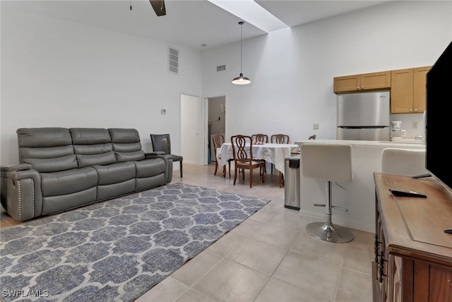 tiled living room with ceiling fan and a high ceiling