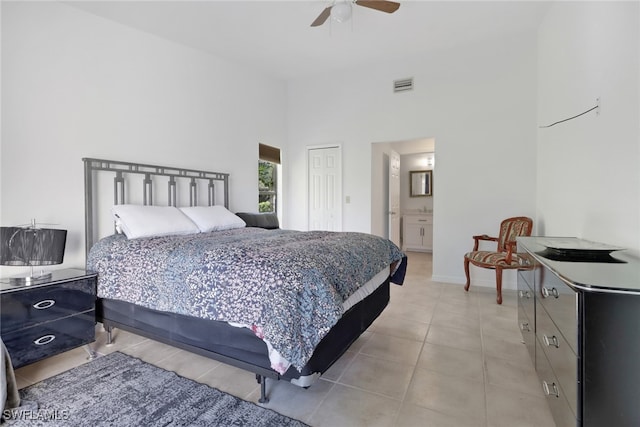 bedroom with a high ceiling, light tile patterned floors, a closet, ensuite bathroom, and ceiling fan