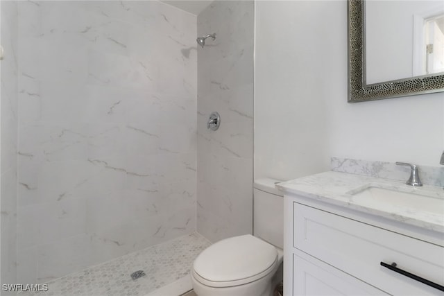 bathroom featuring tiled shower, toilet, and vanity