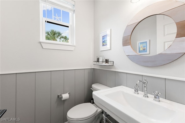 bathroom with a wainscoted wall, a sink, and toilet