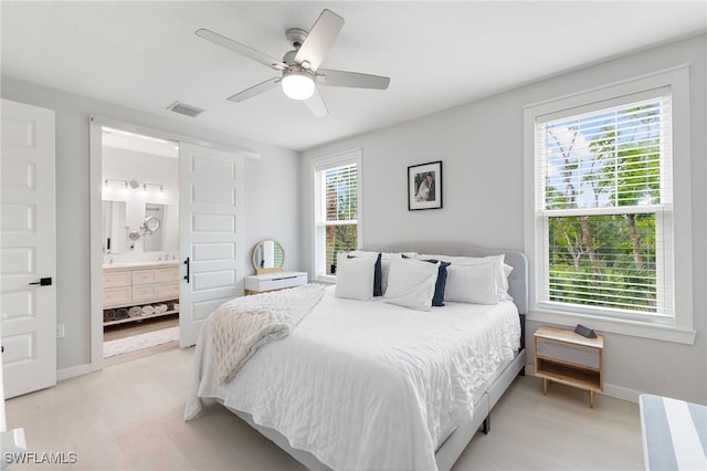 bedroom with baseboards, visible vents, ceiling fan, and ensuite bath
