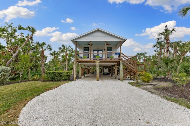 coastal inspired home featuring a carport, a front yard, ceiling fan, and covered porch