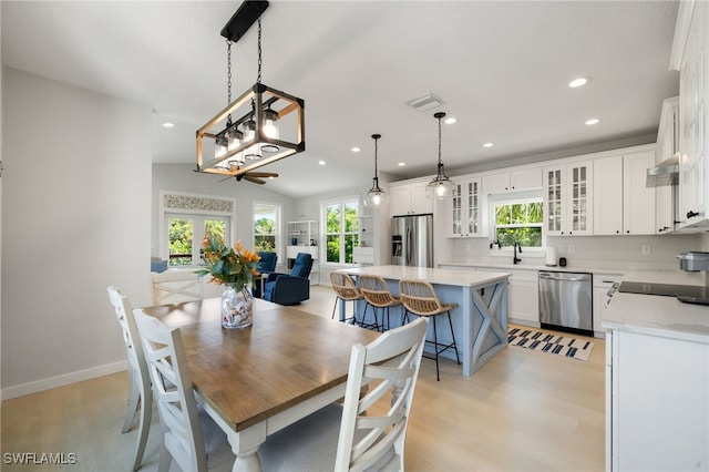 dining space with visible vents, vaulted ceiling, light wood-type flooring, and plenty of natural light