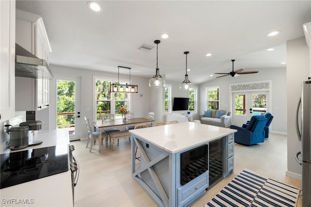 kitchen with wine cooler, freestanding refrigerator, exhaust hood, visible vents, and a healthy amount of sunlight