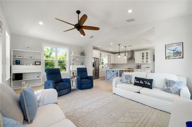 living area featuring lofted ceiling, visible vents, recessed lighting, and a ceiling fan