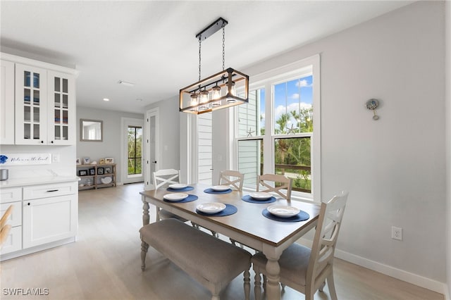 dining space featuring baseboards, light wood-type flooring, and a notable chandelier