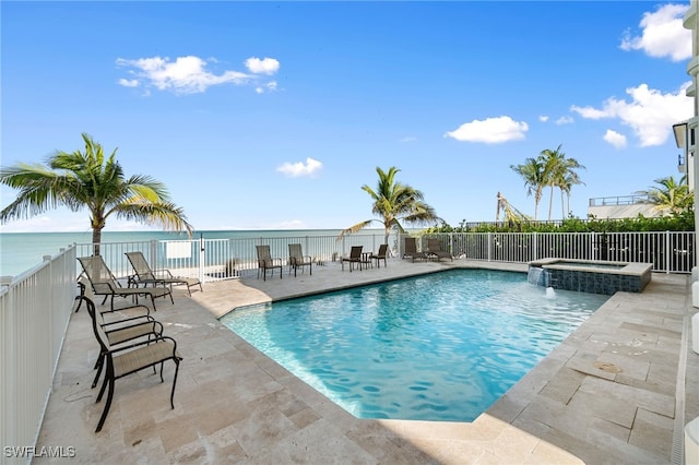 view of pool with a pool with connected hot tub, a patio area, a water view, and fence