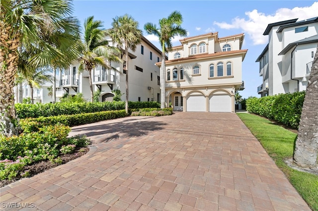 view of front facade featuring a garage, a residential view, decorative driveway, and stucco siding