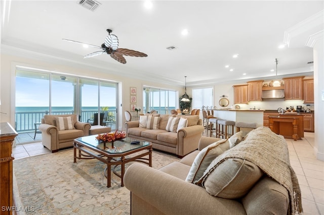 tiled living room with crown molding, ceiling fan, and a water view