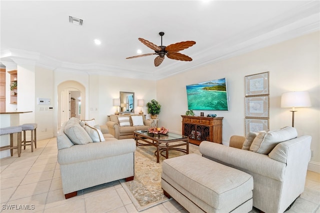 living room with arched walkways, ceiling fan, visible vents, baseboards, and ornamental molding