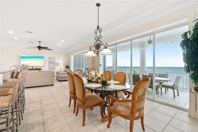 tiled dining area featuring ornamental molding, ceiling fan with notable chandelier, and a water view