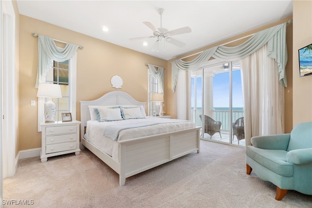 bedroom with light carpet, access to outside, a water view, and recessed lighting