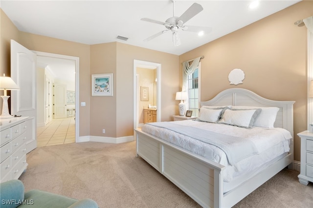 bedroom with light carpet, a ceiling fan, visible vents, baseboards, and ensuite bath