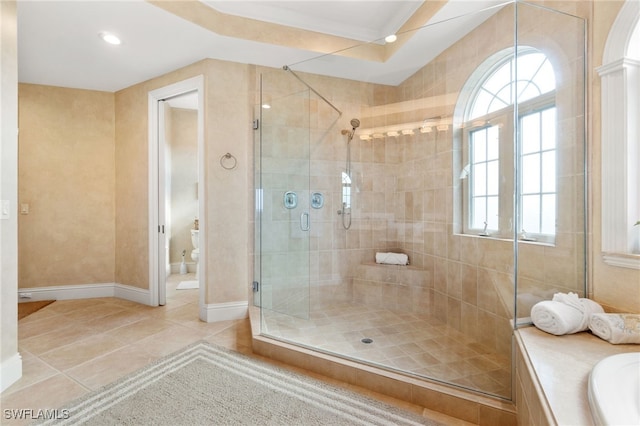 bathroom with a washtub, toilet, a stall shower, baseboards, and tile patterned floors