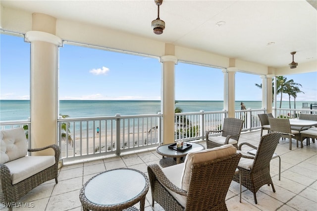 view of patio featuring a water view, a view of the beach, and a balcony