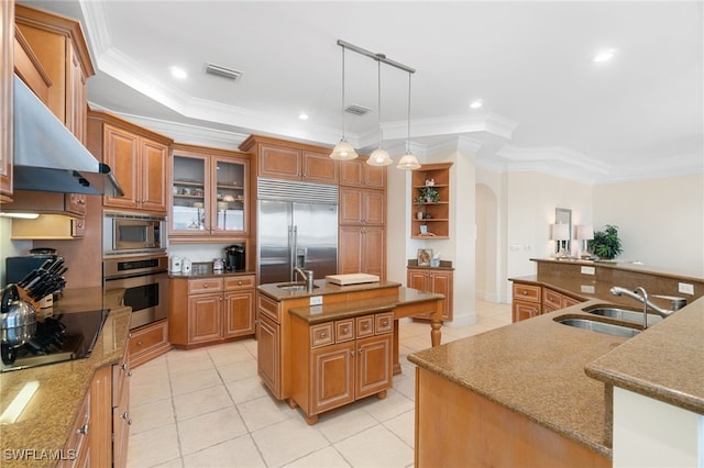 kitchen with arched walkways, glass insert cabinets, a sink, an island with sink, and built in appliances