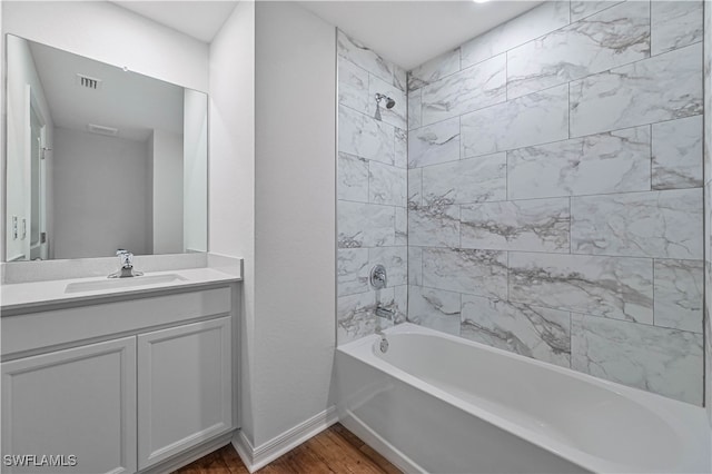 bathroom featuring wood-type flooring, tiled shower / bath combo, and vanity