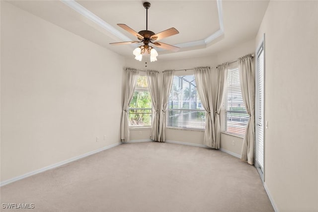 empty room with crown molding, light colored carpet, ceiling fan, and a tray ceiling