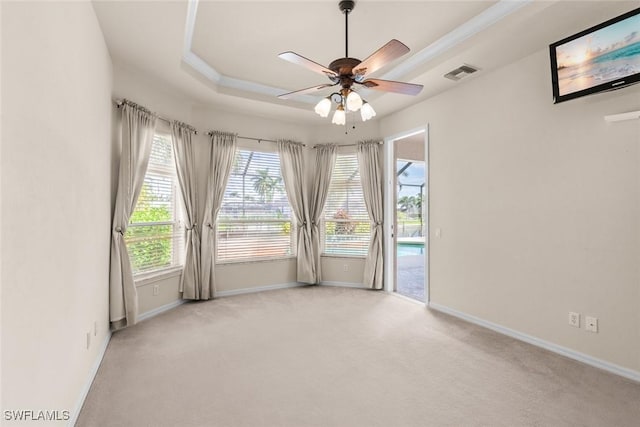 unfurnished room with a raised ceiling, crown molding, light colored carpet, and ceiling fan