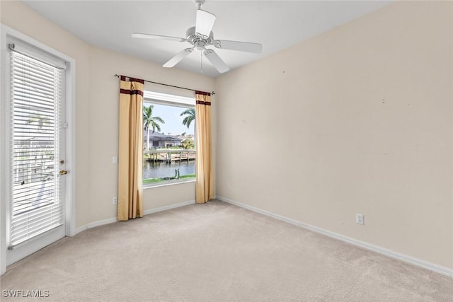 carpeted spare room featuring a water view and ceiling fan