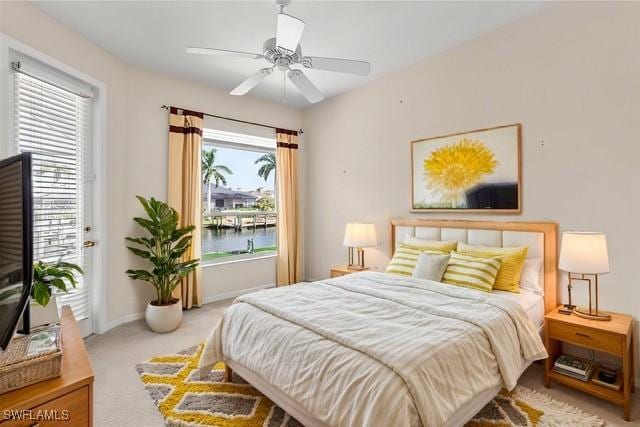 carpeted bedroom featuring a water view and ceiling fan