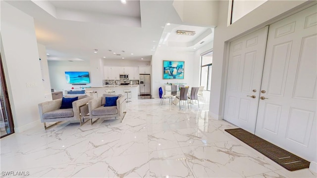 foyer with marble finish floor, recessed lighting, a raised ceiling, and baseboards