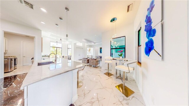 kitchen with pendant lighting, sink, light tile patterned floors, and light stone countertops