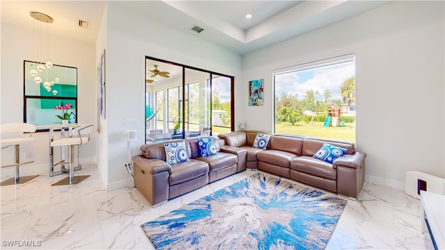 living room with a tray ceiling and light tile patterned floors